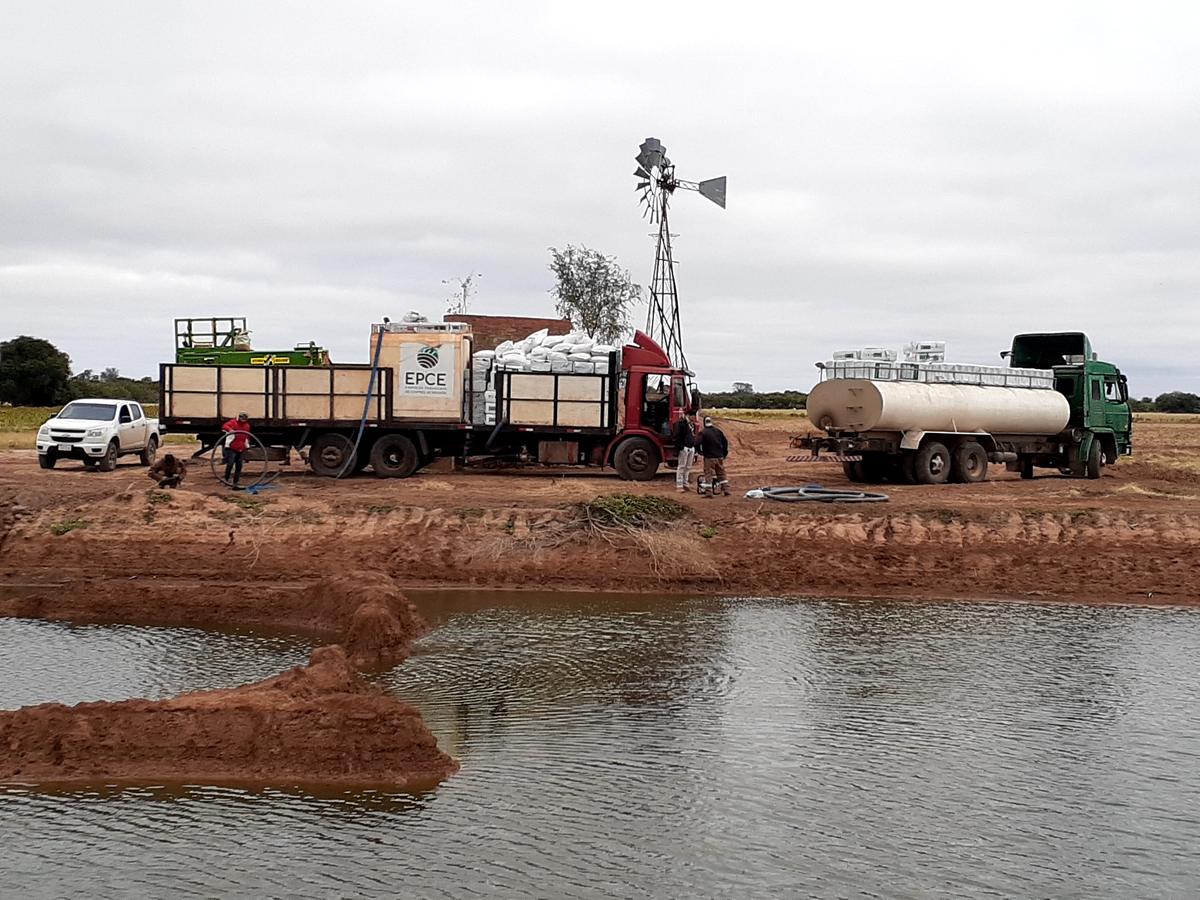 El equipo cargando agua en un tajamar, con el molino al fondo