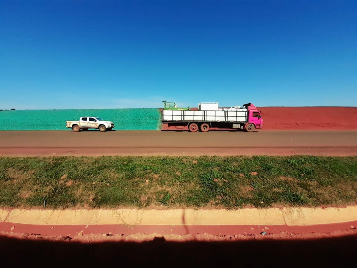 Camión sobre la ruta de tierra roja, con la franja hidrosembrada