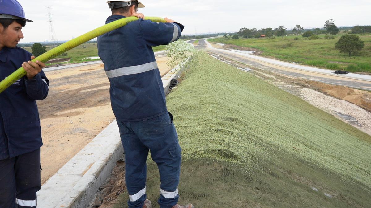 Operario llevando la manguera al hombro sobre el talud
